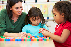 teacher working with two girls on blocks and counting